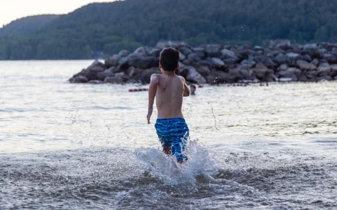 Child running into the water at a lake beach