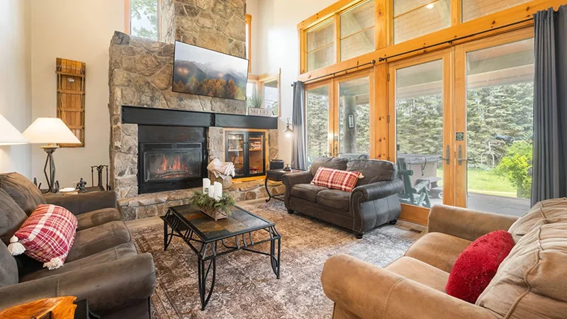 Vacation home living room with a stone fireplace, sofas, and large windows