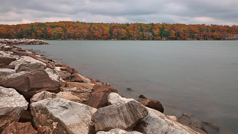 Rocky shoreline along Deep Creek Lake with fall foliage across the water